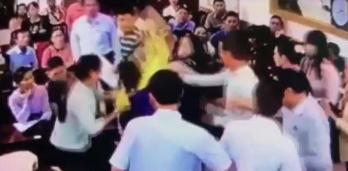 Trần Thị Phi Yến (áo khoác vàng) đang hành hung bà Mỹ Anh bằng túi xách cầm trên tay tại phiên đấu giá. (ảnh cắt từ clip).