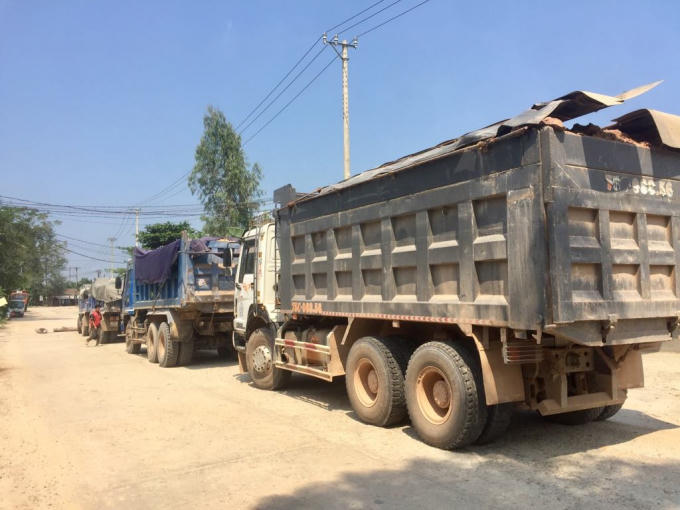Nhiều xe chở đất được che bạt sơ sài khiến đất đá rơi vãi xuống đường gây bụi bặm.