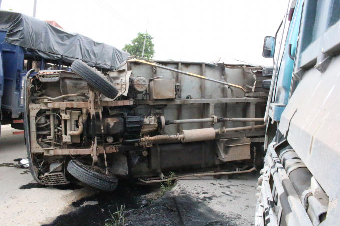 Xe tải lật nằm chắn ngang đường, hư hỏng nặng.