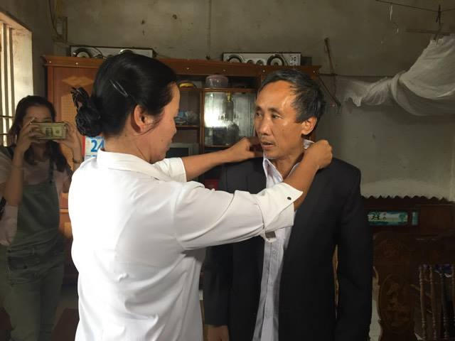 Bà Nguyễn Thị Mai chỉnh lại quần áo cho chồng trước khi ra trụ sở UBND xã Phúc Sơn.