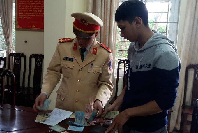 Thượng úy CSGT kiểm tra lại toàn bộ tài sản trong ví để trao trả lại cho anh Hoàng.