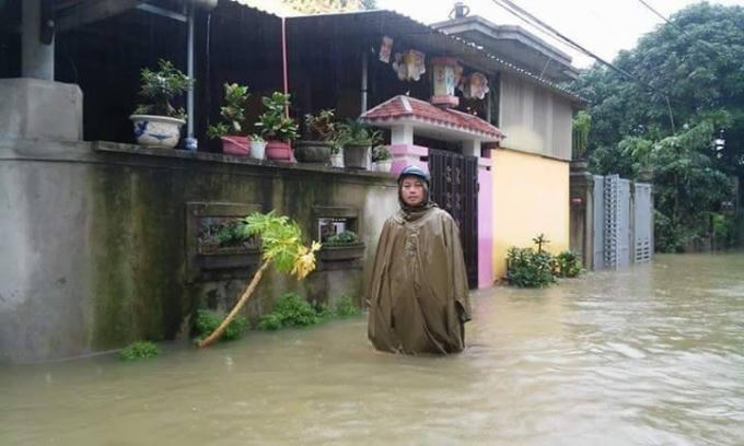 Một người dân lội giữa một biển nước đi mua thức ăn tối.