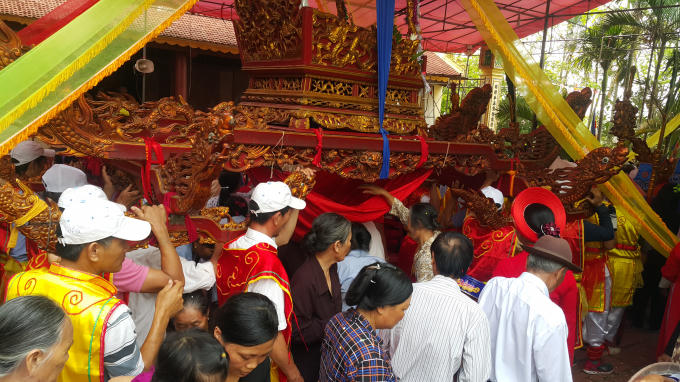 Kể từ lúc những người khiêng kiệu đứng thẳng lên và bắt đầu di chuyển, khung cảnh bắt đầu nhộn nhịp. Từ người già cho đến trẻ cứ đua nhau ném tiền lẻ vào miếng vải điều bốn góc cột bốn chân kiệu, miếng vải võng xuống thành chỗ chứa công đức.
