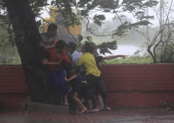 Bão Thần Sấm đổ bộ vào Manila, Philippines năm 2014 khiến người dân phải bám chặt vào cây để không bị thổi bay. (Ảnh: Reuters)