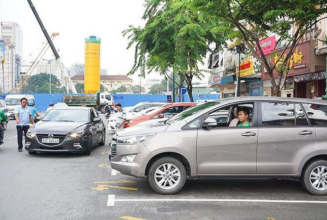 Nhân viên đô thị hướng dẫn tài xế cho xe vào bãi đỗ có thu phí