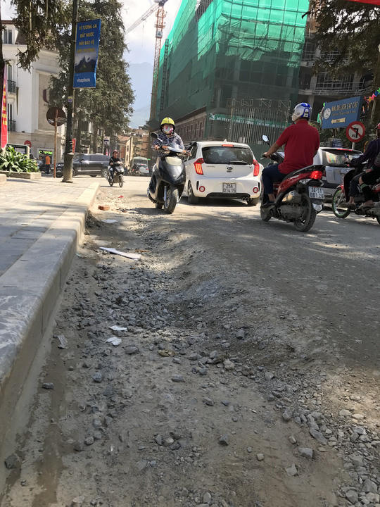 Con đường quanh sân vận động trung tâm bị cày nát, lộ ra những mảng đất đá gây bụi bặm, ai đi qua cũng phải bịt mũi.