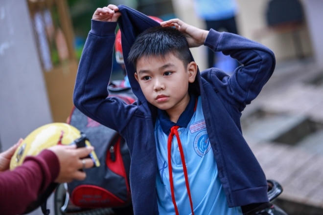 Không đợi mẹ nhắc vì trời lạnh, bé Vũ Anh Khôi (Tiểu học Đinh Tiên Hoàng, quận 1) tự mặc áo ấm khi vừa bước chân ra cổng trường.