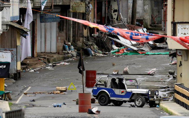 Sau một tuần kể từ ngày Maute, nhóm phiến quân từng thề trung thành với IS, tấn công thành phố Marawi trên đảo Mindanao miền nam Philippines hôm 23/5, quân đội chính phủ tuyên bố đã giành quyền kiểm soát thành phố này. Tuy nhiên, vẫn còn một số khu vực nhất định đang bị phiến quân Maute chiếm đóng buộc quân đội chính phủ phải dốc toàn lực để “dẹp loạn”. Trong ảnh: Một khu vực tại Marawi bị nhóm Maute chiếm giữ với cờ IS (màu đen) được cắm ngay giữa đường đi.