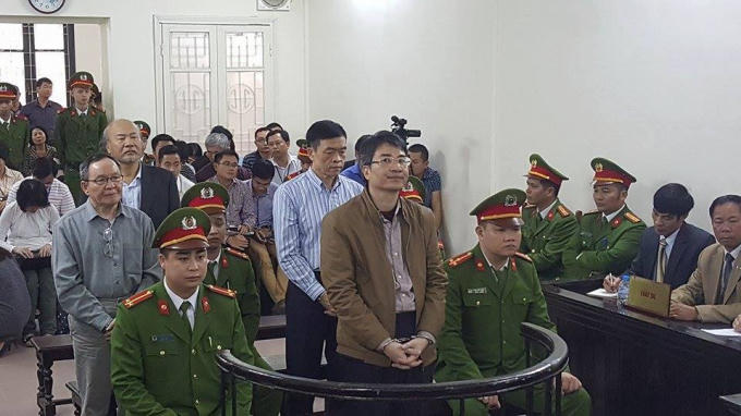 Các bị cáo đứng trước vành móng ngựa trong phiên tòa.