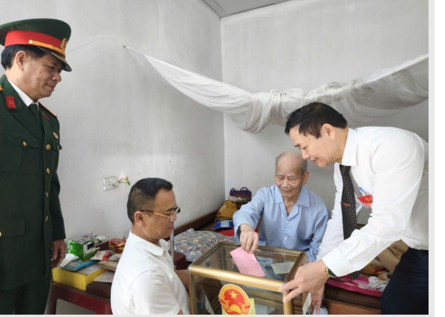 Cử tri cao tuổi thực hiện quyền bầu cử tại nhà với sự hỗ trợ của tổ bầu cử và lực lượng chức năng trong ngày bầu cử 15/3. (Ảnh: Hoàng Nga).