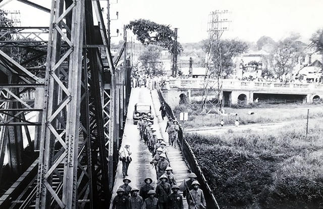 Một đơn vị Quân đội Nhân dân Việt Nam đang tiếp quản cầu Long Biên. Phía sau là các sĩ quan Pháp đang làm thủ tục bàn giao và rút khỏi Hà Nội, ngày 9/10/1954.