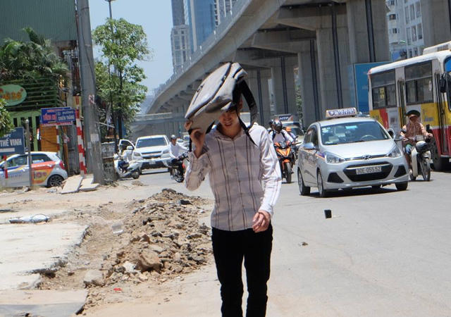 Một thanh niên phải dùng ba lô che lên đầu tránh nắng