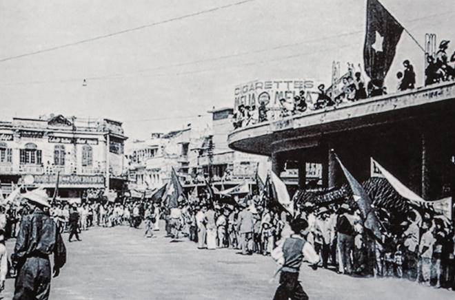1954: Khi quân Pháp rút đi, hàng chục ngàn người dân Hà Nội đã đổ ra đường để chào đón những người chiến sĩ quân giải phóng về tiếp quản Thủ đô. Trong ảnh là đoàn người hân hoan cùng cờ đỏ sau vàng và băng rôn, khẩu hiệu chào mừng trên tay tại Ngã Năm Bờ Hồ, nay là Quảng trường Đông Kinh Nghĩa Thục.