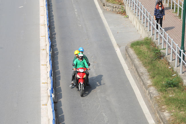 Một tài xế GrabBike chở 3 đi vào làn của xe BRT ở phố Giảng Võ.