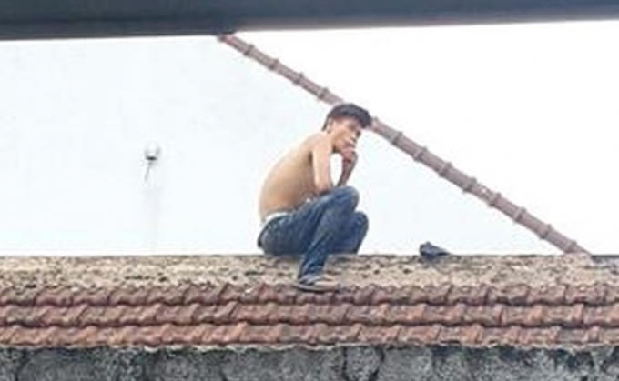 Nam thanh niên nghi ngáo đá cố thủ hòa hét trên mái nhà. (Ảnh: MĐ)
