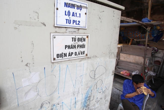 Một người đàn ông ăn sáng bên cạnh chiếc hộp điện khổ lớn trên đường Lê Duẩn (Đống Đa).