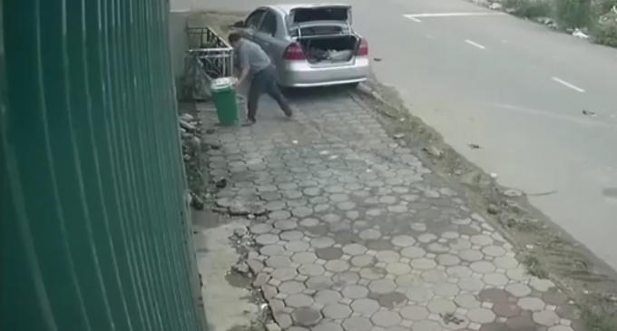 Người đàn ông xuống xe nhấc chiếc thùng rác cho vào cốp.