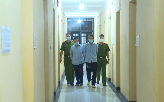 Lực lượng Công an dẫn giải hai đối tượng cầm đầu sàn tiền ảo. Ảnh: Báo Nhân Dân
