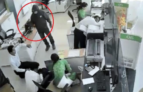 Tên cướp liên tục nạt nộ, dọa bắn các nhân viên, yêu cầu gom tiền bỏ vào 2 túi xách. Ảnh: Cắt từ video.