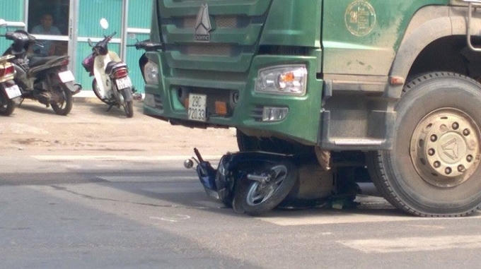 Hiện trường vụ tai nạn, chiếc xe máy không còn nguyên vẹn nằm trong gầm ô tô. (Ảnh: Dương Khang).
