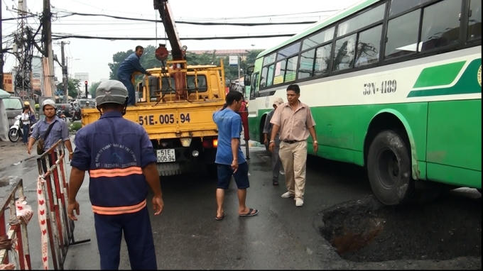 Bánh xe buýt nằm trên miệng hố.