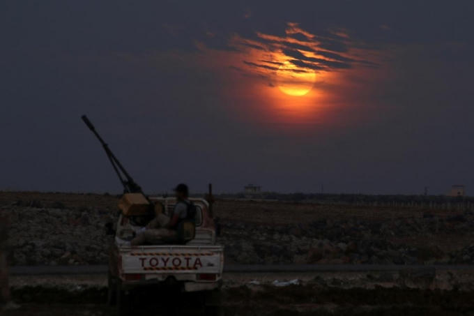 Một tay súng của lực lượng Quân đội Syria Tự do ngồi trên chiếc xe tải mang vũ khí ở thị trấn Dael, Deraa, Syria khi siêu trăng bắt đầu xuất hiện. (Ảnh: Reuters)