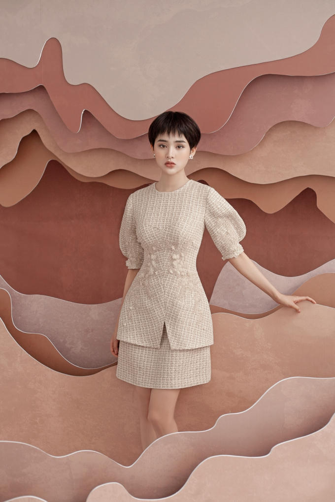 Chiếc đầm cổ tròn, tay phồng cổ điển hút mắt hơn nhờ phần chân váy được cách điệu và xếp lớp. Nhà mốt chọn họa tiết ren kết hợp hoa vải điểm xuyến nơi tay áo, eo váy mang đến cảm giác thon gọn cho ngoại hình.