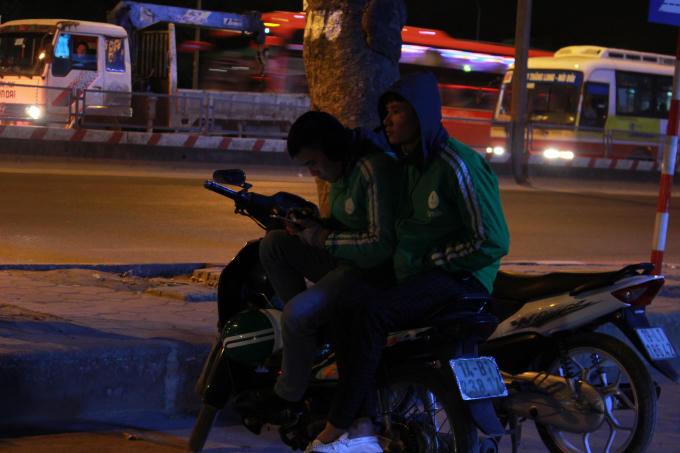 ...tài xế xe ôm Grab đang co ro chờ khách.