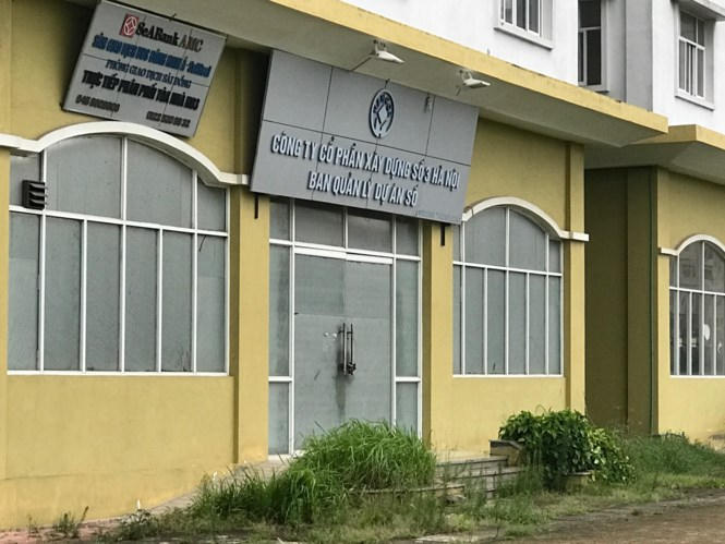 Cỏ mọc ngập ống chân quanh khu nhà, nhiều thiết bị vệ sinh, tủ điện đã han gỉ rất nặng. Do lâu không được vệ sinh nên rác thải ngập quanh khu nhà khiến nơi đây càng thêm hoang tàn, hôi hám. Trong ảnh: Cỏ hoang lấp cả đường vào khu nhà