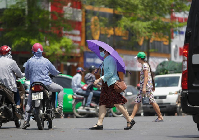 Hai người phụ nữ vội vã sang đường ở phố Xã Đàn.
