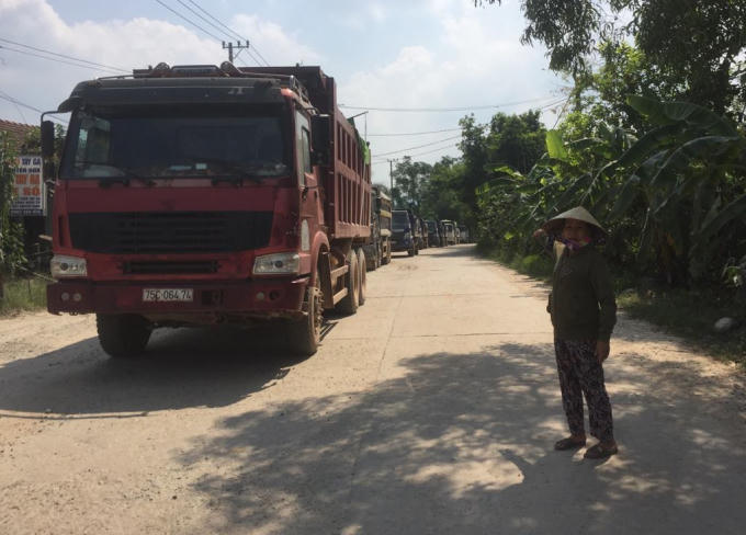 Đoàn xe tải nối đuôi nhau nằm yên bất động vì rào chắn của người dân chưa được tháo dở.