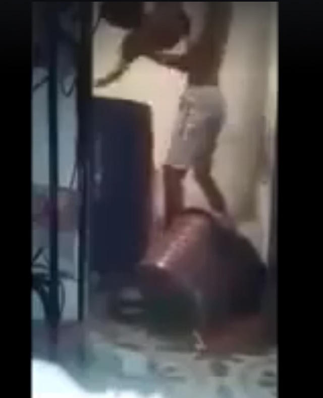 Hình ảnh người đàn ông đang dìm hai em nhỏ vào lu nước. (Ảnh cắt từ clip)