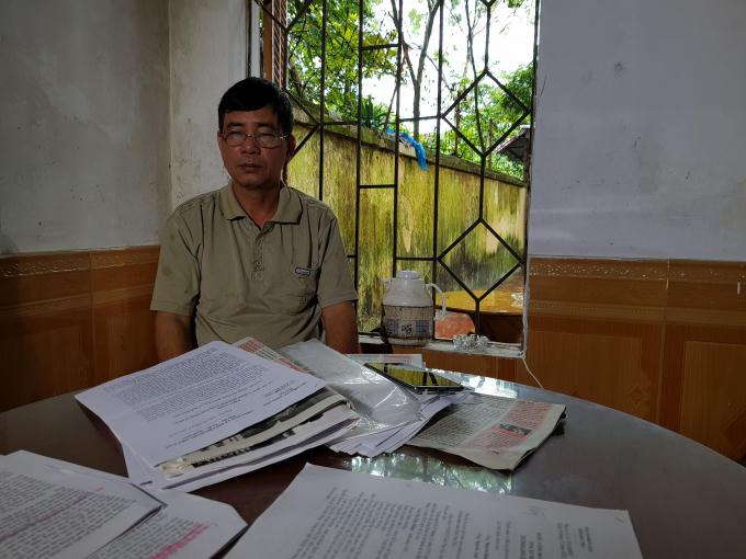 Ông Sự thẫn thờ bên những tài liệu kêu oan cho con gái.