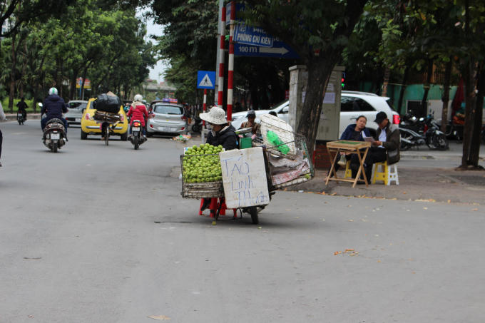 Cô bán táo rong trên đường Hoàng Quốc Việt đang co ro bên xe táo.