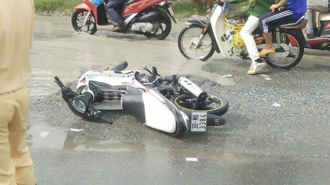 Do mặt đường bị hư hỏng và mưa lớn khiến người điều khiển xe máy bị mất tay lái ngã xuống đường.