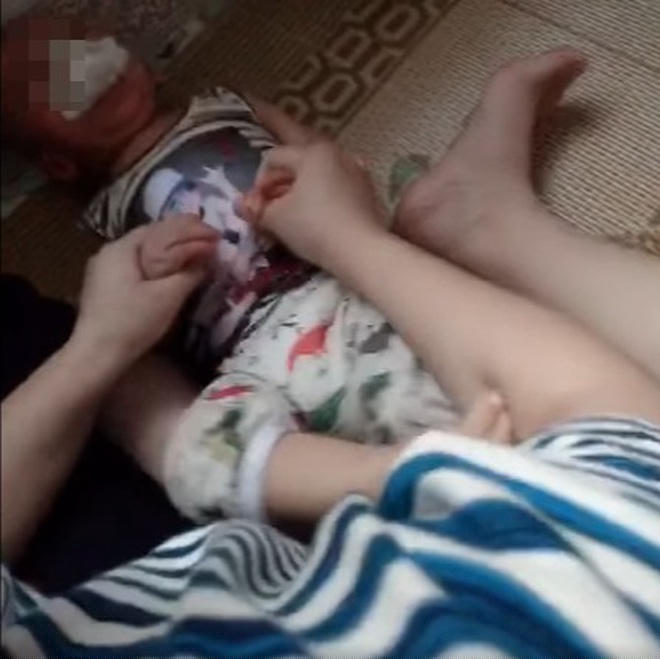 Cháu bé đang giãy giụa vì bị nhét giẻ vào miệng (Ảnh: Cắt từ clip). 