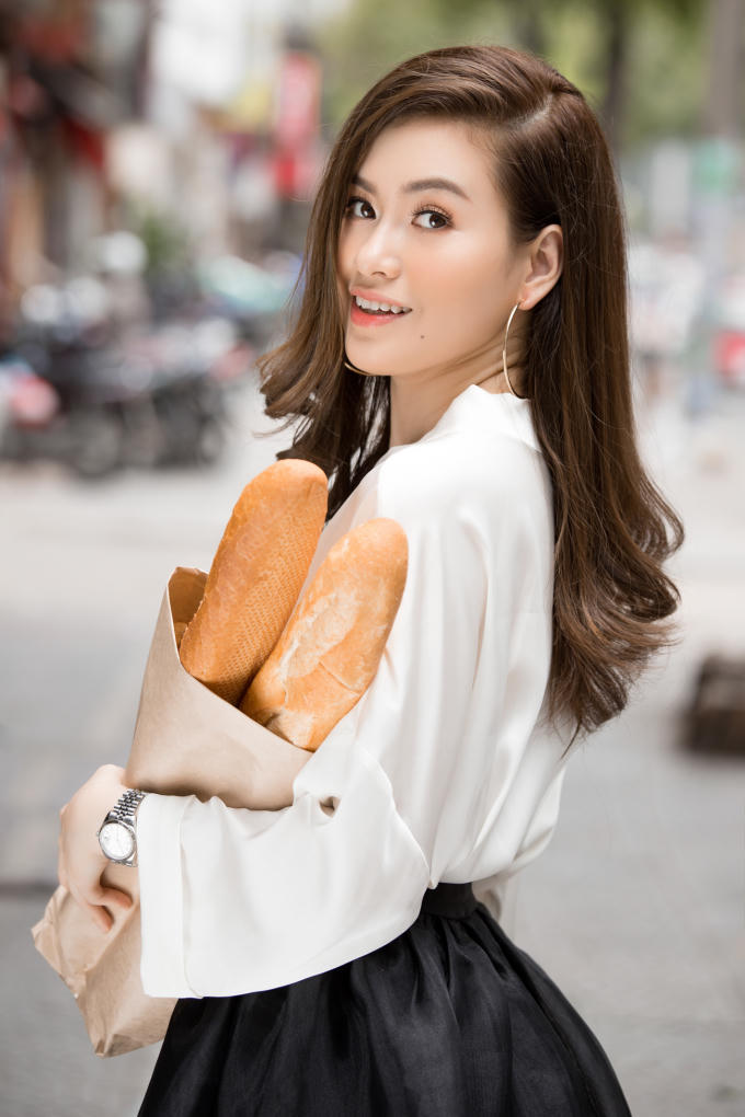 Trong những bức hình này, Hoa hậu Diễm Trần hóa cô gái bán bánh mỳ yêu kiều trên phố. Chiếc áo sơ mi dáng rộng kết hợp cùng chân váy kiểu công chúa càng làm tôn lên vẻ nữ tính và dịu dàng của nàng Hoa hậu.