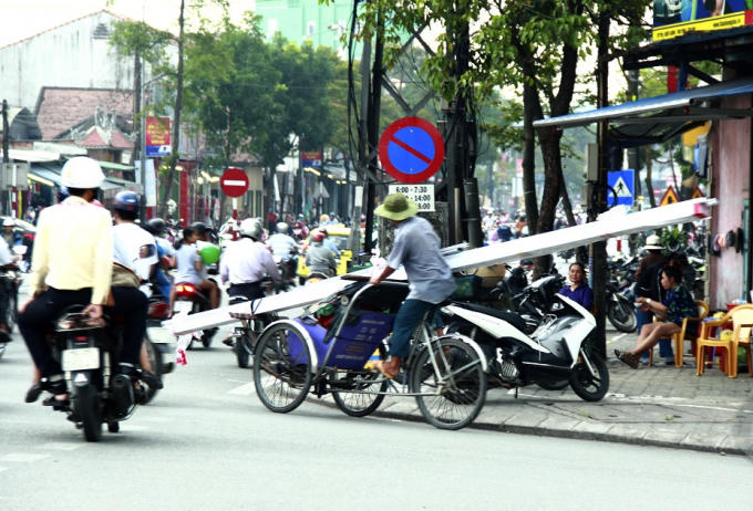 Một chiếc xích lô chở những thanh nhôm dài cả chục mét lưu thông trên đường Hùng Vương (TP Huế).