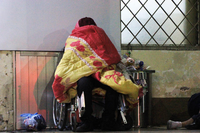 Người đ&agrave;n &ocirc;ng ngồi tr&ecirc;n chiếc xe lăn lấy chăn ch&ugrave;m k&iacute;n m&iacute;t, tr&aacute;nh những cơn gi&oacute; r&eacute;t buốt