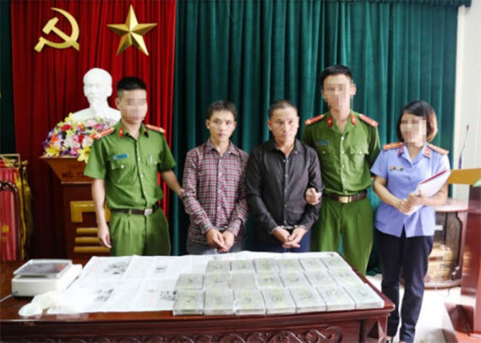 Đối tượng Lầu Bá Cha và Lầu Bá Vừ cùng 20 bánh heroin tại cơ quan điều tra.