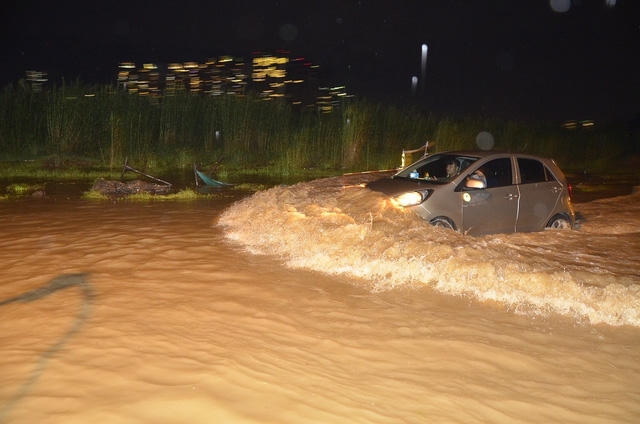 Một chiếc ô tô chạy nhanh tạo sóng trên đường.