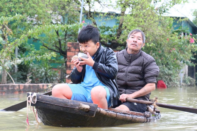 Một cậu bé phấn khởi khi được tiếp tế nắm xôi trên hành trình vượt lũ.