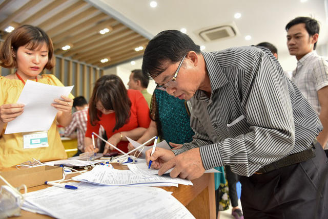 Không còn chỗ ngồi, nhiều khách hàng phải đứng để điền thông tin vào mẫu kê khai trước khi chụp ảnh chân dung.