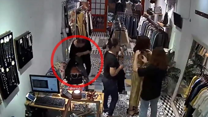 Hình ảnh người phụ nữ nghi ngờ đang lục túi xách được đặt trên ghế sofa.