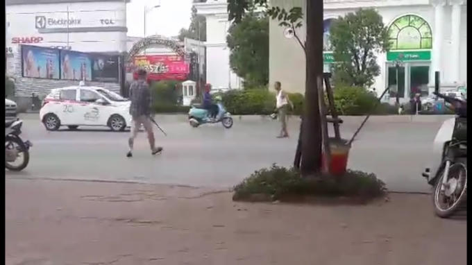 Nam thanh niên cầm theo gậy rút lao ra đường tấn công người đàn ông lớn tuổi.