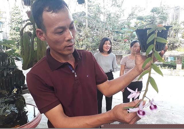 Anh Tuất đang giới thiệu lan cho khách đến mua và tham quan tại vườn.