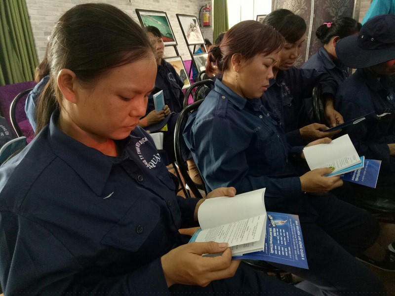 Các công nhân đọc sổ tay pháp lý lao động. Ảnh: TRÚC PHƯƠNG