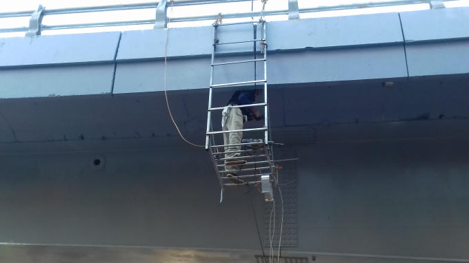 Một công nhân đang treo mình trên thành cầu để kiẻm tra chi tiết hạng mục.