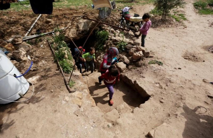 Hàng ngày, cậu bé Ali Khaled Stouf (14 tuổi) phải bước xuống vài bậc để đến lớp học nằm bên trong một cái hang ở ngôi làng Tramla, hiện do phe đối lập nắm giữ ở tỉnh Idlib, phía Tây Bắc Syria. (Ảnh: Reuters)