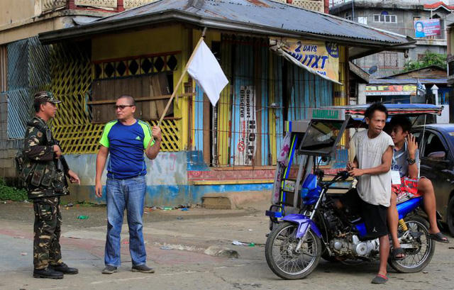 Một người dân cầm cờ trắng khi nói chuyện với một binh sĩ Philippines tại Marawi. Hành động này được cho là nhằm giúp họ tránh bị trở thành mục tiêu tấn công nhầm của các máy bay quân đội đang tiến hành không kích nhóm phiến quân Maute.